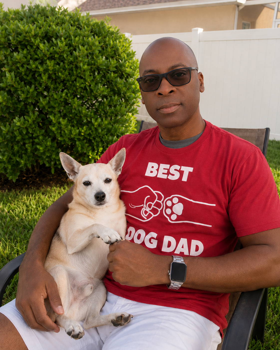 Sammie Cooper seated outdoors with his dog Gaius on his lap.